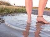 Helle Feinstrumpfhose und Strandschuhe in der Pfütze