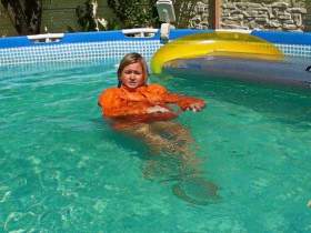 Christina in einem Pool in Moncler Daunenjacke und Realise Gummi-Badeanzug