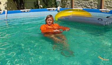 Christina in einem Pool in Moncler Daunenjacke und Realise Gummi-Badeanzug
