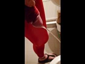 Pissing at home in red legging with penis sleeve